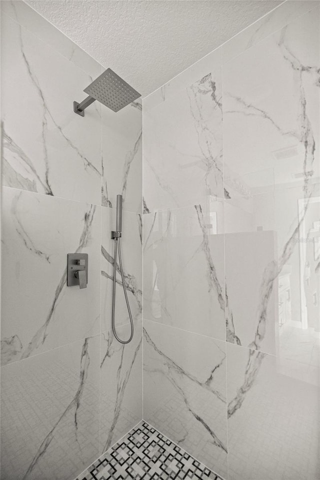 bathroom with a textured ceiling and a marble finish shower