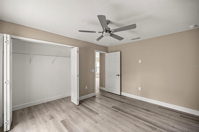 unfurnished bedroom with light wood-style floors, a closet, a textured ceiling, baseboards, and a ceiling fan