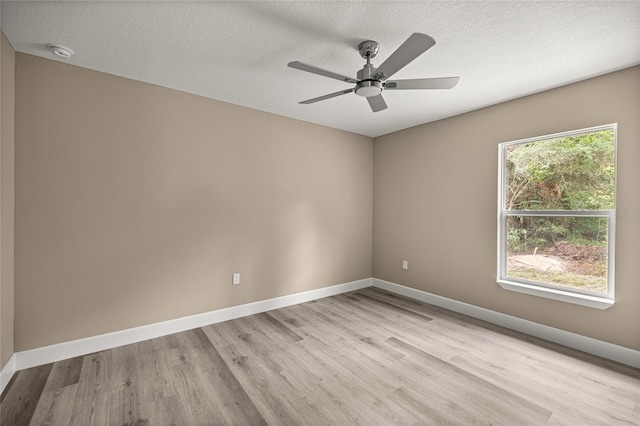 empty room featuring light wood-style floors, a smoke detector, baseboards, a textured ceiling, and a ceiling fan