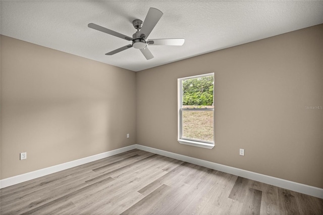 empty room featuring light wood-style floors, baseboards, a ceiling fan, and a textured ceiling