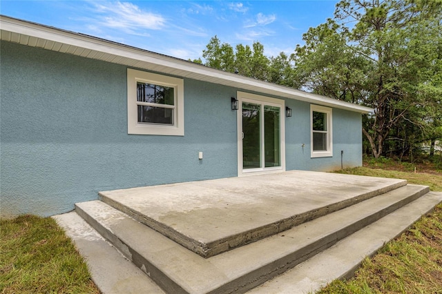 back of property with stucco siding and a patio
