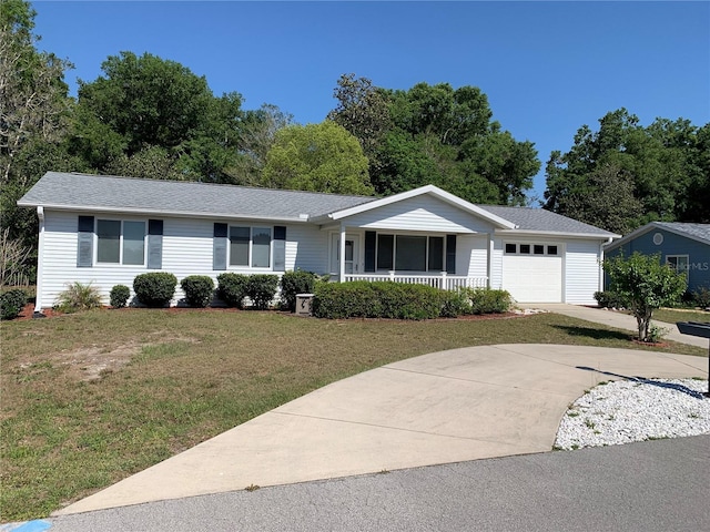 single story home with a porch, an attached garage, a front yard, and driveway