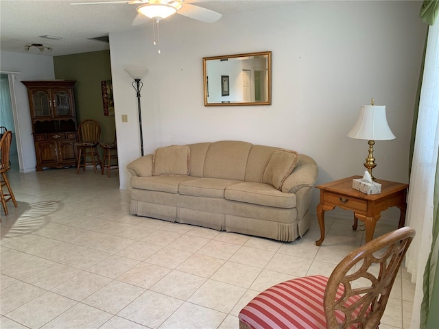 living area featuring ceiling fan, light tile patterned flooring, and a textured ceiling