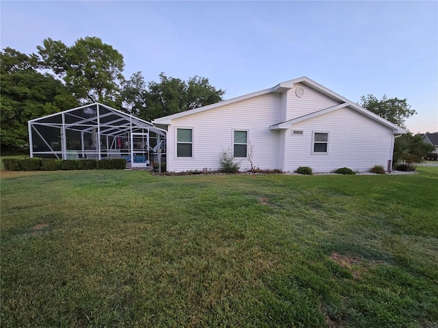 rear view of property with a lawn and a lanai