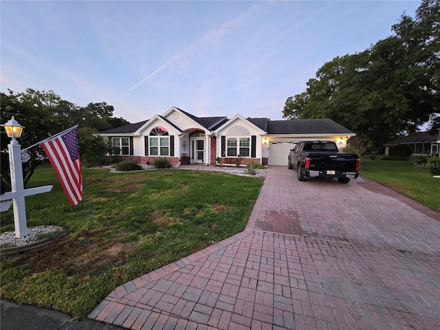 single story home featuring a garage, a front yard, decorative driveway, and brick siding