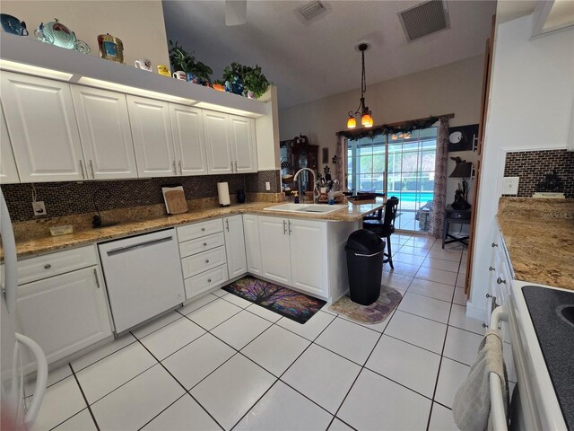 kitchen featuring dishwasher, a sink, decorative backsplash, and a peninsula