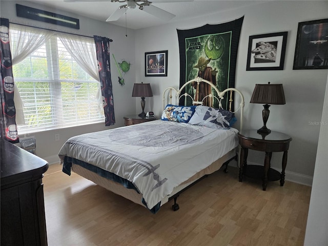 bedroom featuring baseboards, wood finished floors, and a ceiling fan