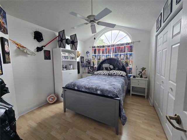 bedroom featuring light wood-type flooring, vaulted ceiling, a closet, a ceiling fan, and baseboards