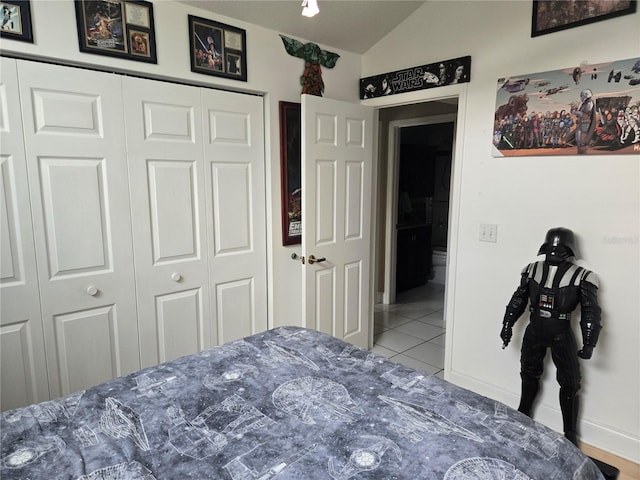 bedroom featuring lofted ceiling, tile patterned floors, a closet, and baseboards