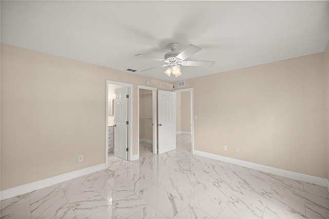 unfurnished bedroom featuring baseboards, light marble finish flooring, and a walk in closet