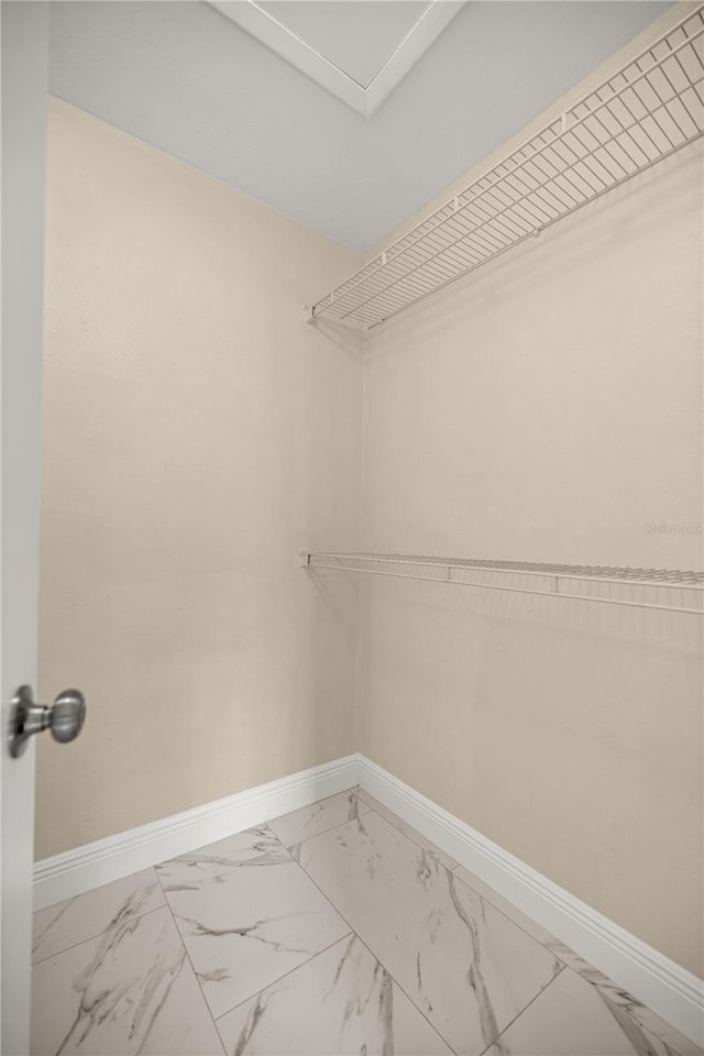 walk in closet featuring light marble finish flooring