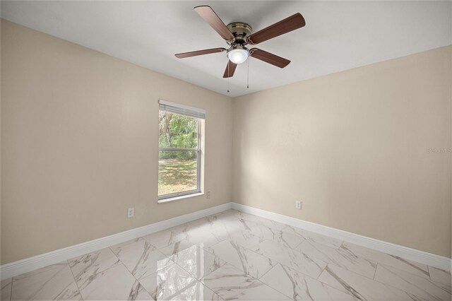 empty room with light marble finish floors, baseboards, and ceiling fan