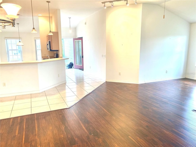 1402 Arredondo Dr, The Villages, FL 32162 - unfurnished living room with vaulted ceiling, wood finished floors, track lighting, and baseboards
