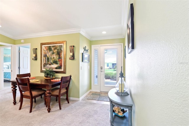 dining room featuring light colored carpet, crown molding, and baseboards