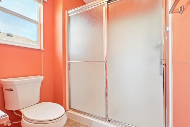 bathroom with a stall shower, toilet, and tile patterned floors