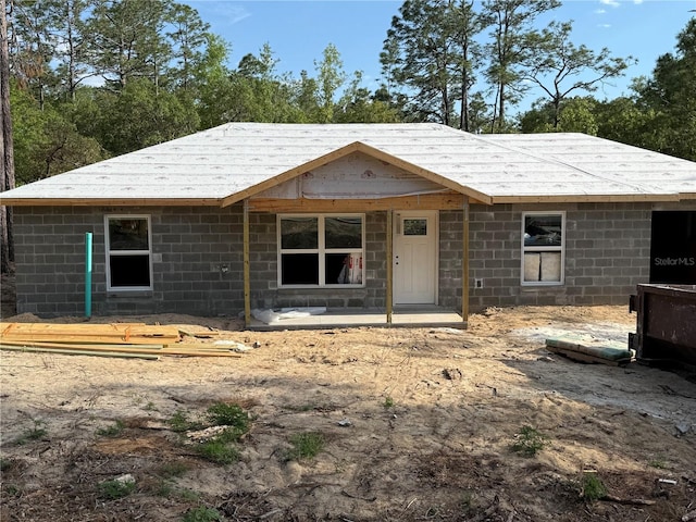 property under construction featuring concrete block siding and roof with shingles