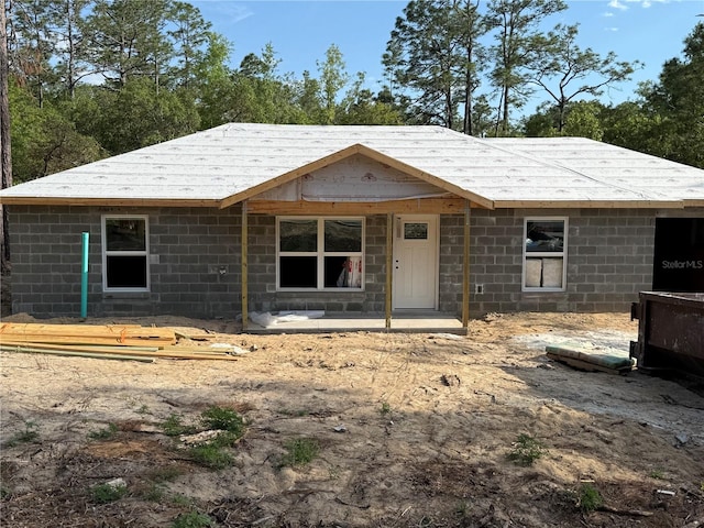 rear view of property featuring concrete block siding and a shingled roof