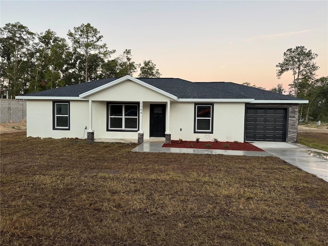 ranch-style home featuring stucco siding, an attached garage, a front yard, and driveway