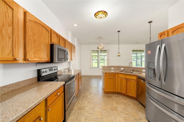 9649 SW 90th St, Ocala, FL 34481 - kitchen featuring appliances with stainless steel finishes, a sink, a peninsula, brown cabinetry, and pendant lighting