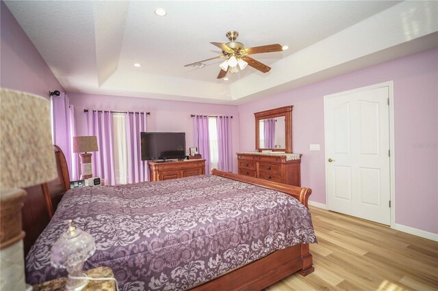 7475 SE 105th Pl, Belleview, FL 34420 - bedroom featuring a tray ceiling, baseboards, light wood finished floors, recessed lighting, and ceiling fan