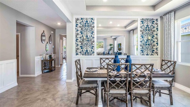 4532 SW 56th Pl, Gainesville, FL 32608 - tiled dining space with a raised ceiling, plenty of natural light, a decorative wall, and wainscoting