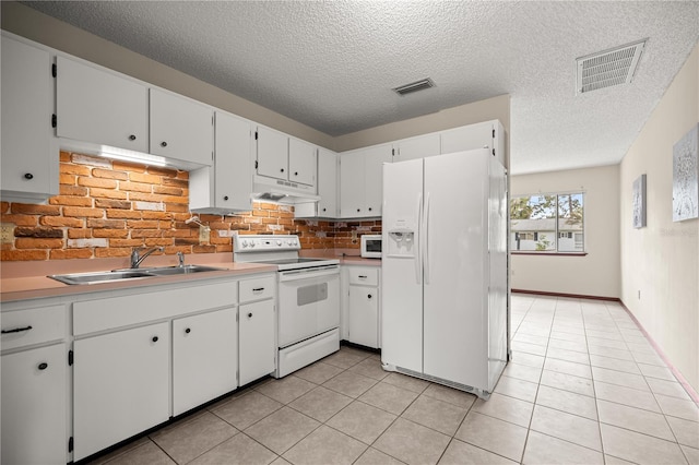 kitchen featuring white appliances, under cabinet range hood, a sink, light tile patterned floors, and light countertops