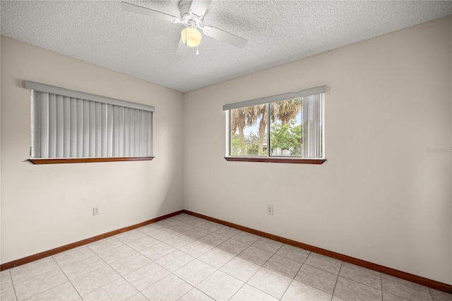 empty room with a textured ceiling, a ceiling fan, and baseboards