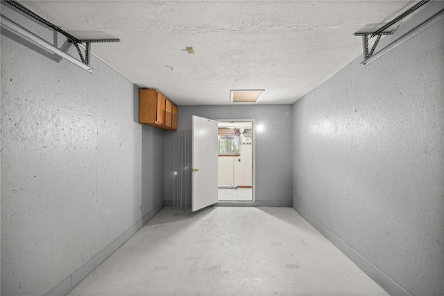 hall with a textured ceiling, a textured wall, and concrete floors