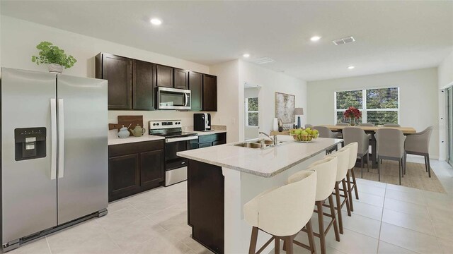 kitchen with a sink, light tile patterned flooring, visible vents, a breakfast bar area, and appliances with stainless steel finishes
