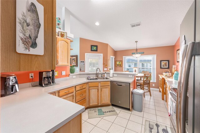 kitchen with appliances with stainless steel finishes, a sink, a peninsula, light countertops, and vaulted ceiling