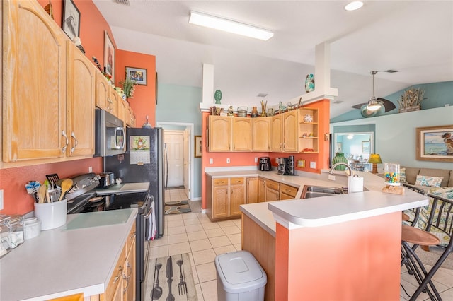 kitchen with stainless steel appliances, a sink, light tile patterned floors, a peninsula, and vaulted ceiling