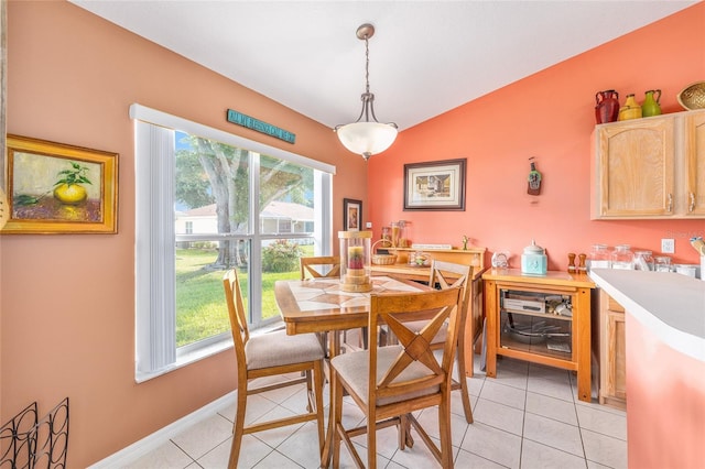 dining room featuring healthy amount of natural light, vaulted ceiling, light tile patterned flooring, and baseboards