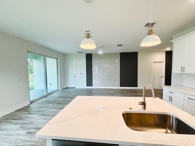kitchen featuring a sink, light wood-style flooring, open floor plan, and hanging light fixtures