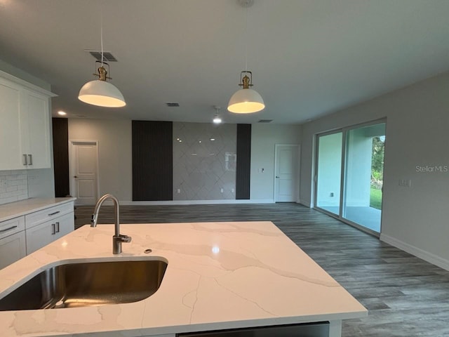 kitchen featuring a sink, open floor plan, wood finished floors, and baseboards
