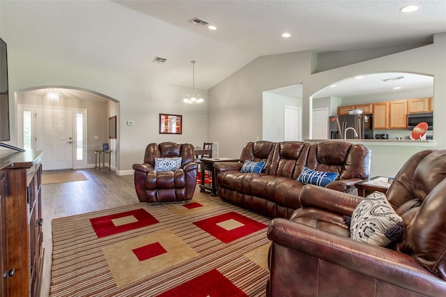 1690 SW 158th Ln, Ocala, FL 34473 - living area with arched walkways, lofted ceiling, a chandelier, wood finished floors, and baseboards