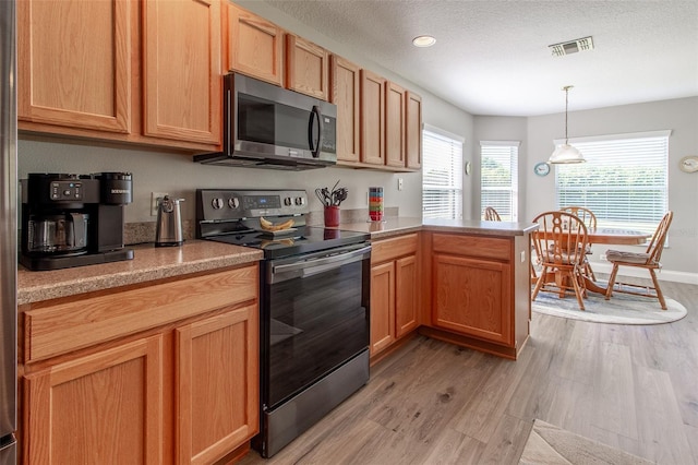 1690 SW 158th Ln, Ocala, FL 34473 - kitchen with stainless steel appliances, light wood-type flooring, a peninsula, light countertops, and pendant lighting