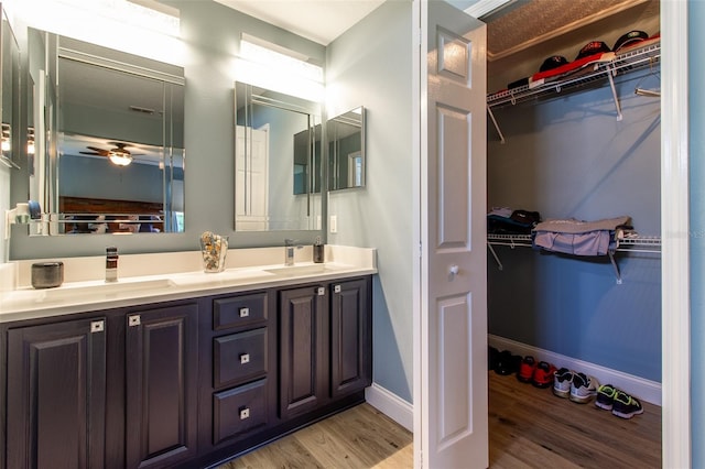 1690 SW 158th Ln, Ocala, FL 34473 - bathroom with wood finished floors, baseboards, double vanity, a ceiling fan, and a walk in closet