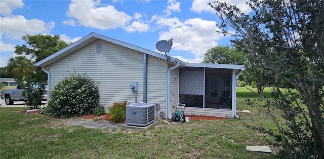 view of side of property featuring central AC, a sunroom, and a lawn