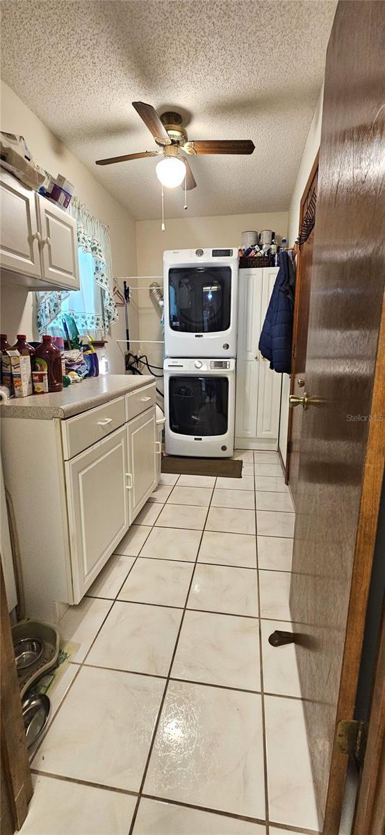 bathroom with stacked washer / dryer, tile patterned flooring, a textured ceiling, ceiling fan, and vanity