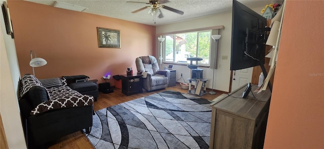 living area featuring wood finished floors, a textured ceiling, and ceiling fan