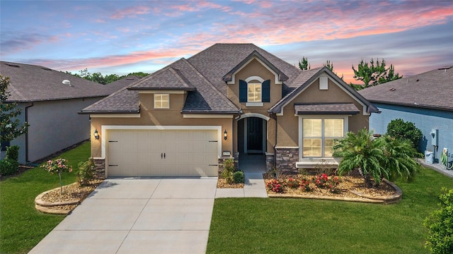 view of front of home featuring stucco siding, roof with shingles, a garage, and a yard