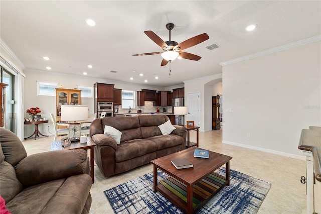 living area with ceiling fan, crown molding, recessed lighting, arched walkways, and baseboards