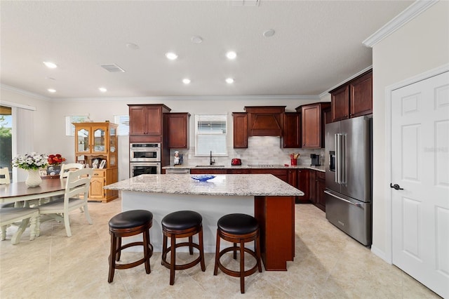kitchen featuring stainless steel appliances, ornamental molding, a kitchen island, a sink, and decorative backsplash