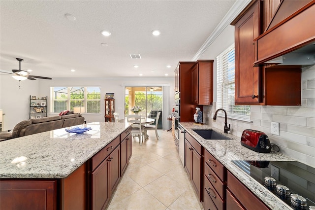 kitchen with black electric cooktop, a sink, a ceiling fan, decorative backsplash, and a kitchen island