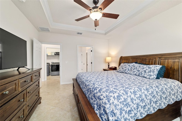 bedroom with a tray ceiling, washer and dryer, ornamental molding, light tile patterned floors, and a ceiling fan