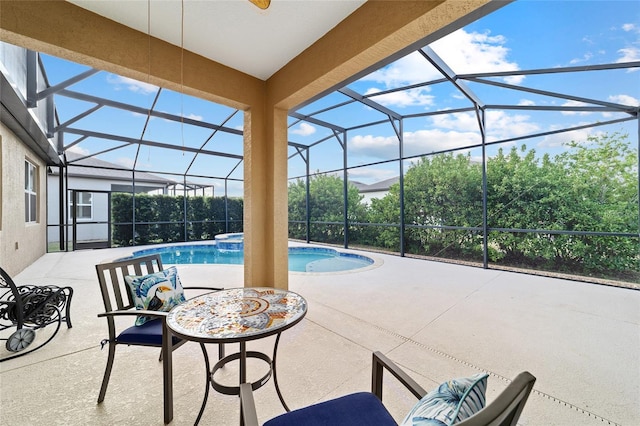 view of pool with a patio, glass enclosure, and a pool with connected hot tub