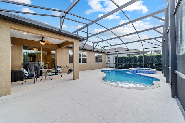 view of pool featuring a patio area, a ceiling fan, a pool with connected hot tub, and glass enclosure