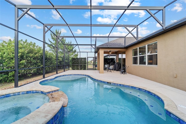view of pool with a patio area, a pool with connected hot tub, glass enclosure, and ceiling fan