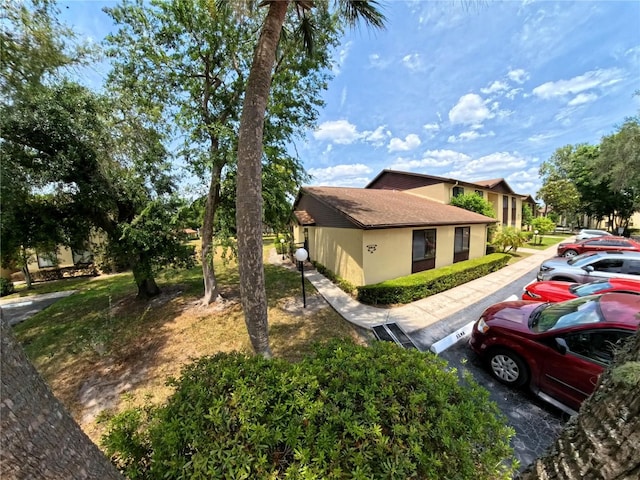 view of home's exterior featuring uncovered parking, roof with shingles, and stucco siding