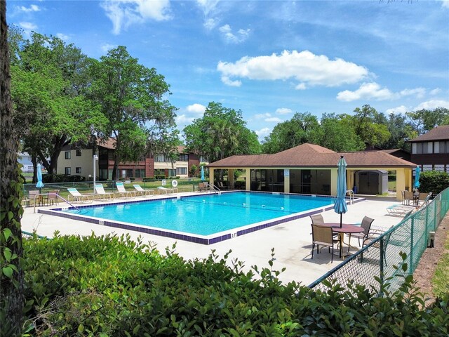 community pool featuring fence and a patio